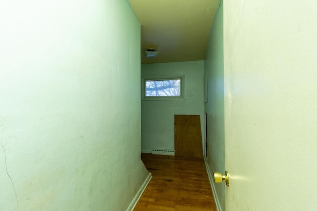 hallway with dark wood-type flooring and a baseboard heating unit