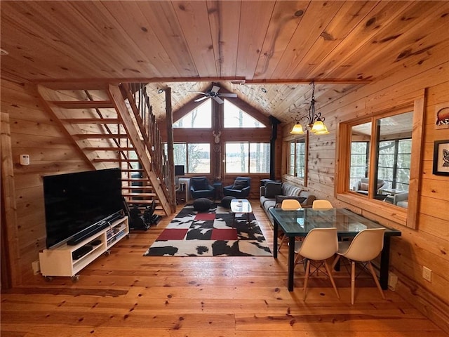 dining room with ceiling fan with notable chandelier, vaulted ceiling, wooden ceiling, and wood walls