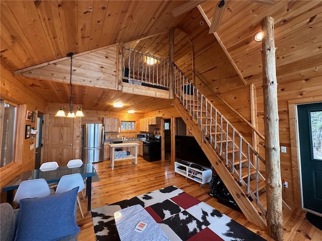 living room with wooden walls, light wood-type flooring, and an inviting chandelier