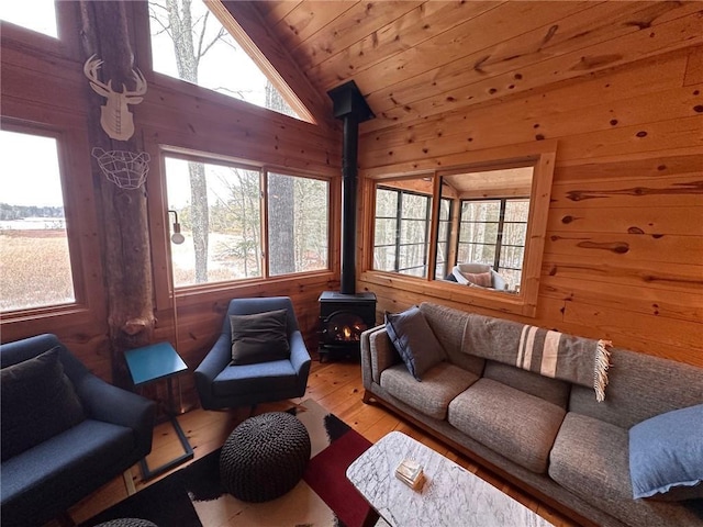 sunroom with a wood stove, a healthy amount of sunlight, wood ceiling, and lofted ceiling