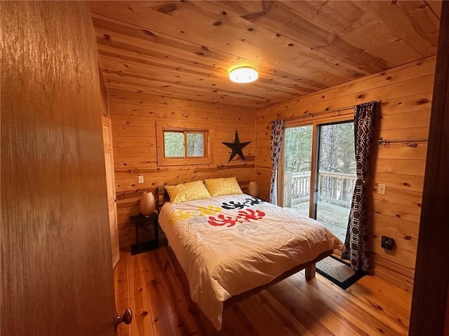 bedroom with hardwood / wood-style floors, wooden walls, wooden ceiling, and access to outside