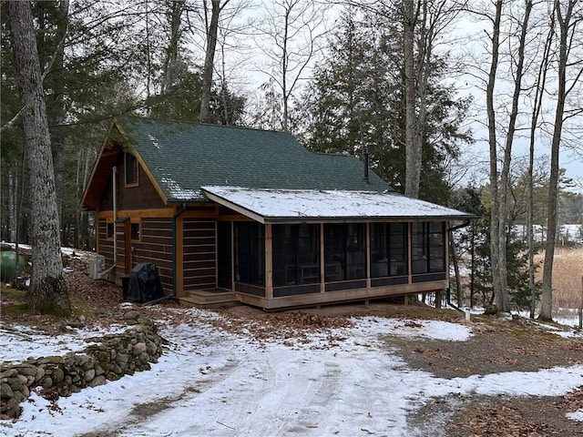 snow covered back of property with a sunroom