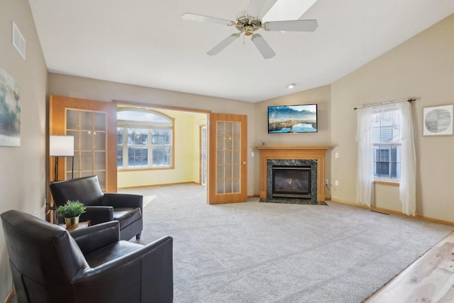 living room featuring ceiling fan, french doors, a premium fireplace, lofted ceiling, and light carpet