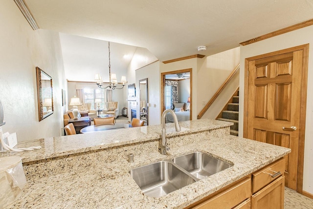 kitchen featuring light stone countertops, ceiling fan with notable chandelier, crown molding, sink, and hanging light fixtures