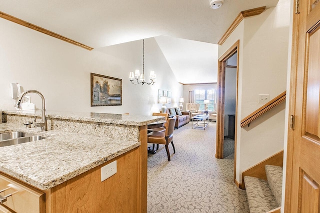 kitchen featuring pendant lighting, light stone countertops, sink, and a chandelier