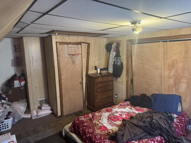 bedroom with a paneled ceiling and wood walls