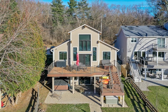 rear view of house with a wooden deck, a patio, and a hot tub