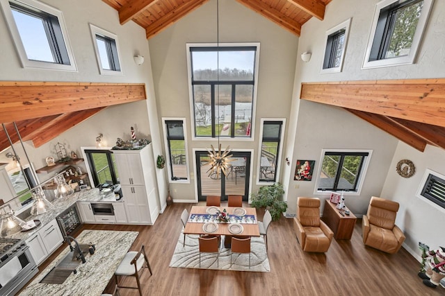 living area featuring light hardwood / wood-style floors, wooden ceiling, sink, and high vaulted ceiling