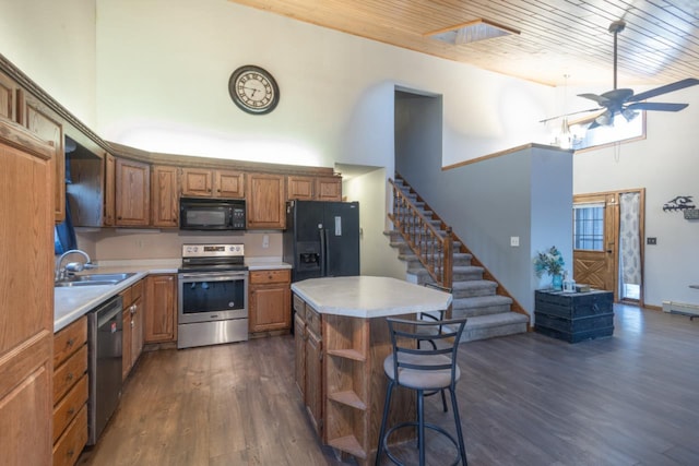 kitchen with a center island, a high ceiling, black appliances, sink, and ceiling fan