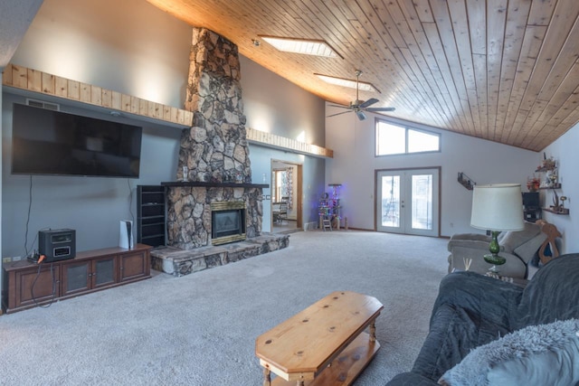 carpeted living room featuring a skylight, ceiling fan, wooden ceiling, a stone fireplace, and high vaulted ceiling