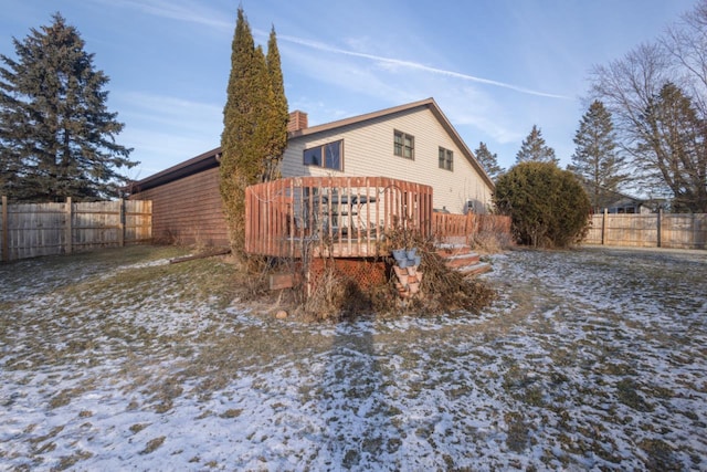 snow covered back of property with a wooden deck