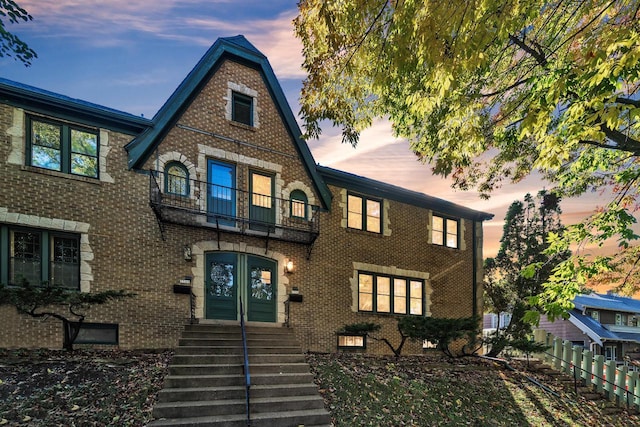 english style home featuring a balcony