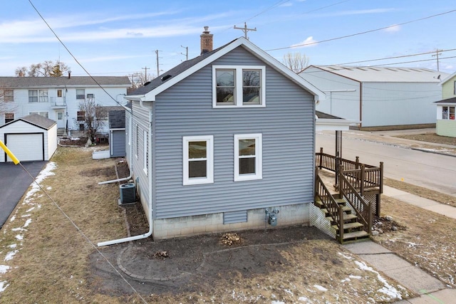 view of property exterior featuring a garage, central air condition unit, and an outbuilding