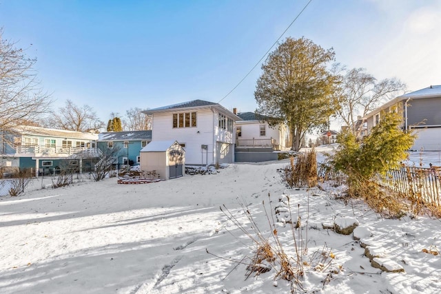 snow covered house featuring a shed