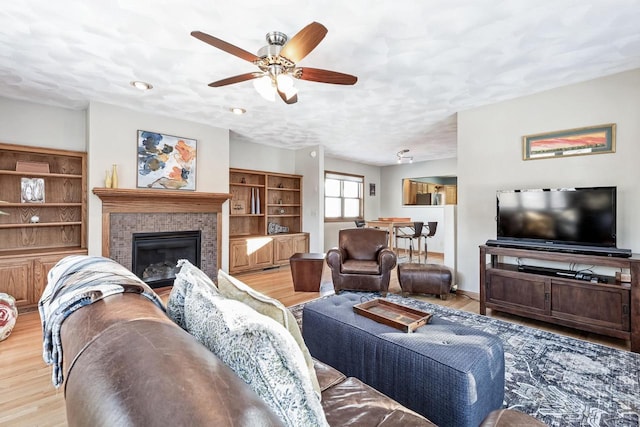 living room featuring ceiling fan, a textured ceiling, and light wood-type flooring