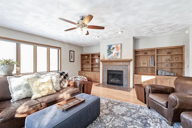 living room featuring a textured ceiling, ceiling fan, and light hardwood / wood-style flooring