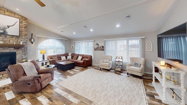 living room featuring hardwood / wood-style floors, vaulted ceiling, and a stone fireplace