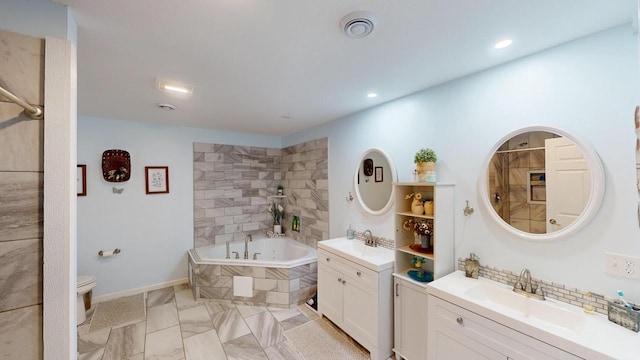 bathroom with tiled tub, vanity, and toilet