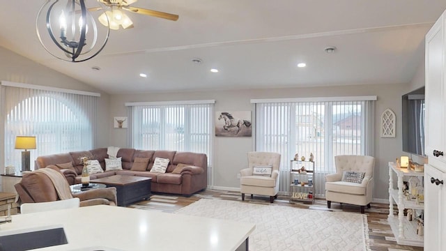 living room with hardwood / wood-style floors, ceiling fan with notable chandelier, and vaulted ceiling