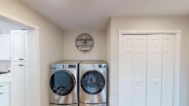 washroom with washer and dryer and cabinets