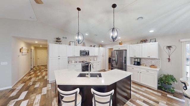 kitchen with appliances with stainless steel finishes, tasteful backsplash, vaulted ceiling, and white cabinetry