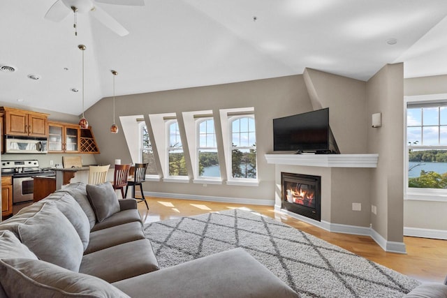 living room featuring light wood-type flooring, vaulted ceiling, and ceiling fan