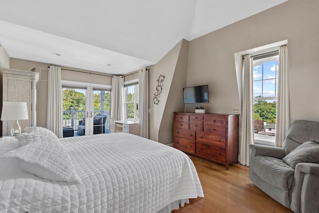bedroom featuring vaulted ceiling, access to outside, and light hardwood / wood-style flooring