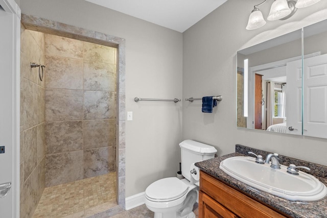 bathroom with tiled shower, vanity, and toilet