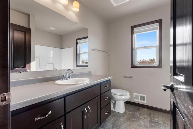 bathroom with walk in shower, vanity, and toilet