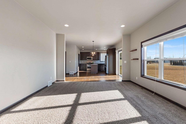 unfurnished living room featuring dark colored carpet and a notable chandelier