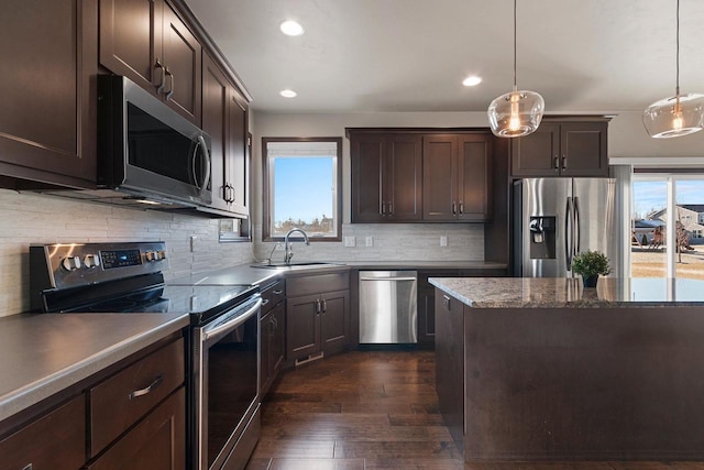 kitchen with appliances with stainless steel finishes, decorative light fixtures, dark brown cabinets, and sink