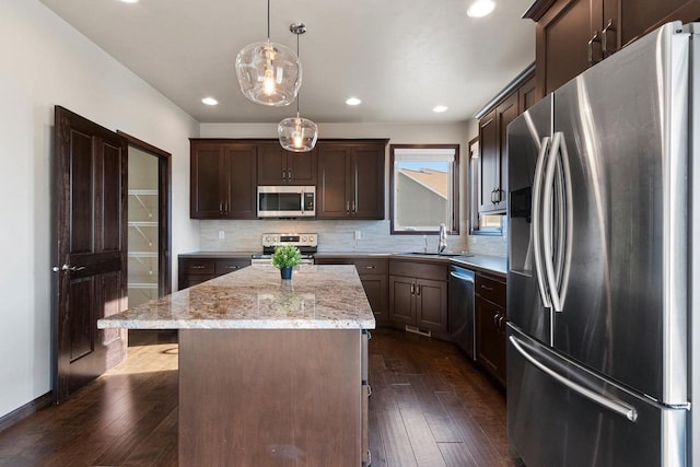 kitchen featuring stainless steel appliances, a kitchen island, hanging light fixtures, and sink