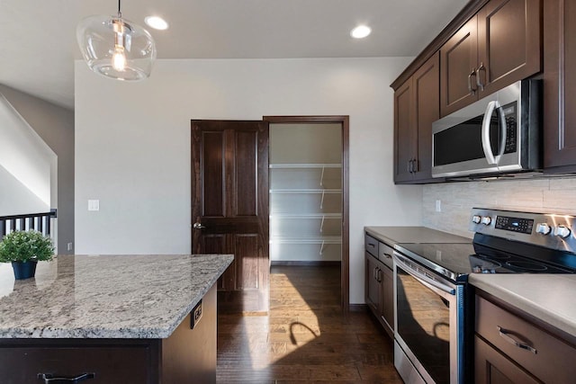 kitchen with decorative backsplash, appliances with stainless steel finishes, dark brown cabinets, dark wood-type flooring, and pendant lighting