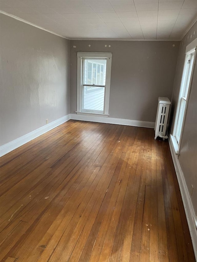 spare room with hardwood / wood-style flooring, a healthy amount of sunlight, radiator heating unit, and ornamental molding