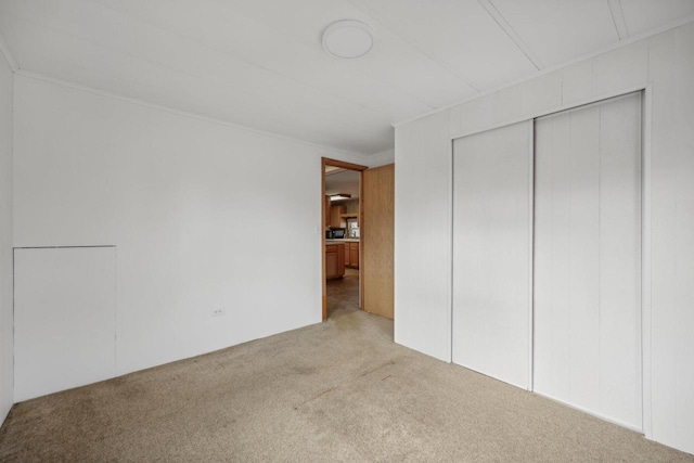 unfurnished bedroom featuring light carpet and a closet