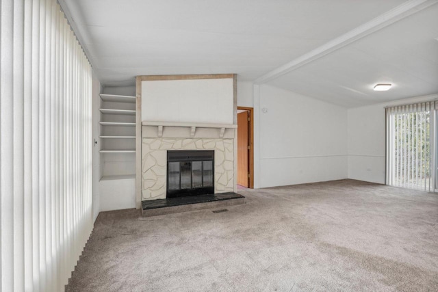 unfurnished living room featuring carpet, beam ceiling, and a stone fireplace