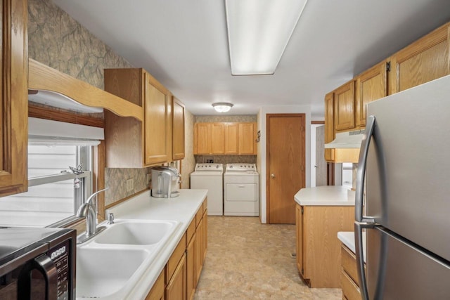 kitchen with washer and dryer, stainless steel refrigerator, and sink