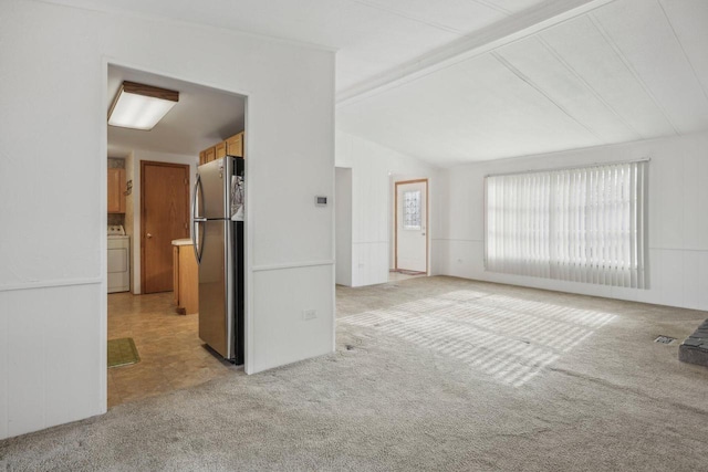 spare room featuring washer / clothes dryer, light carpet, and lofted ceiling with beams