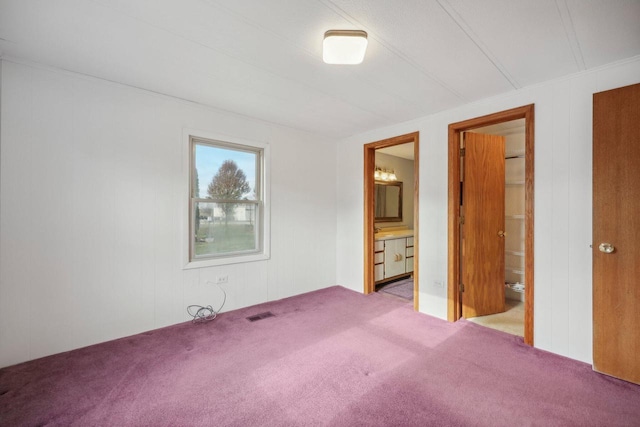 unfurnished bedroom featuring connected bathroom, light colored carpet, a spacious closet, and a closet