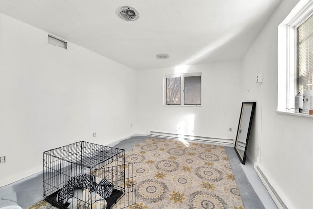 empty room featuring concrete flooring, a wealth of natural light, and a baseboard radiator