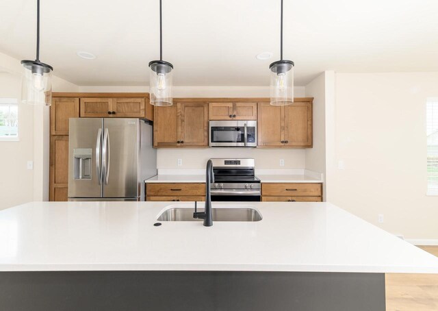 6407 Prairie Wood Dr, Mcfarland, WI 53558 - kitchen featuring a sink, pendant lighting, brown cabinets, light countertops, and appliances with stainless steel finishes