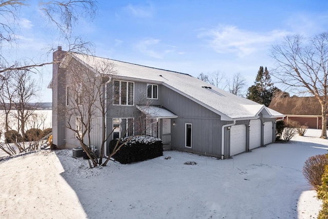 snow covered back of property with a garage