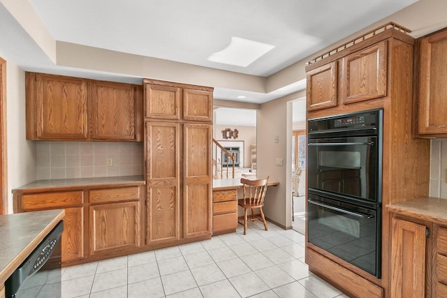 kitchen featuring tasteful backsplash, light tile patterned floors, and black appliances