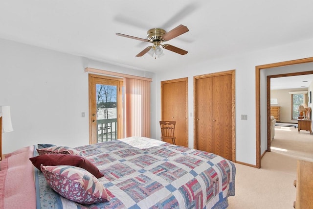 bedroom with a baseboard heating unit, access to outside, light colored carpet, ceiling fan, and multiple closets