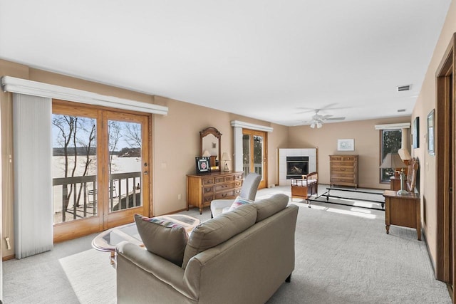 carpeted living room with a tiled fireplace and ceiling fan