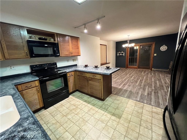 kitchen featuring hanging light fixtures, an inviting chandelier, a baseboard heating unit, kitchen peninsula, and black appliances