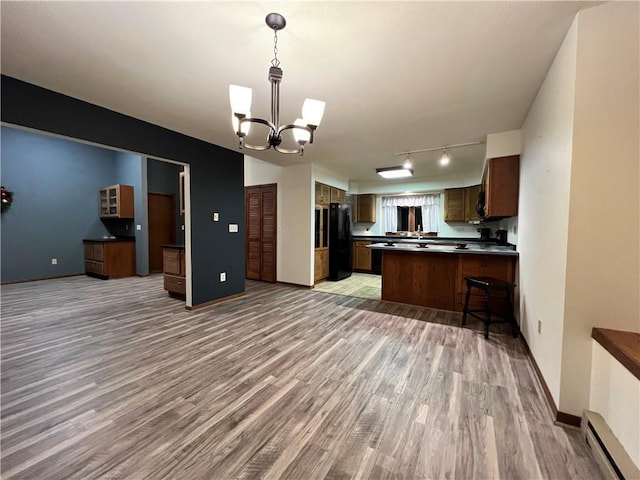 kitchen with an inviting chandelier, black fridge, light hardwood / wood-style flooring, a baseboard heating unit, and kitchen peninsula