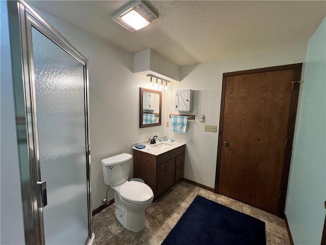 bathroom with vanity, toilet, a shower with door, and a textured ceiling