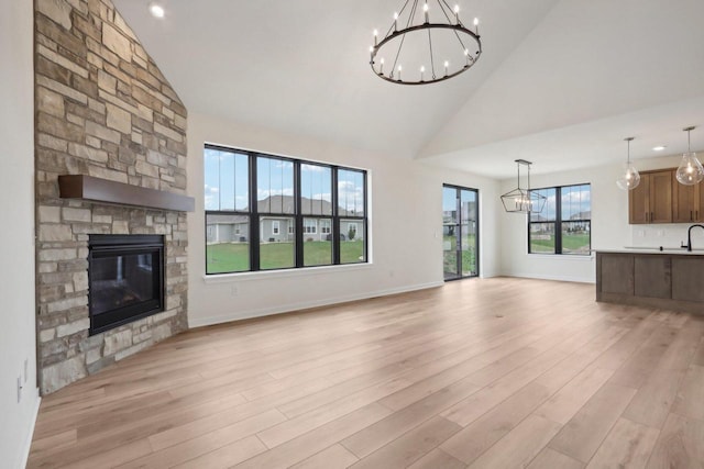 unfurnished living room with a stone fireplace, high vaulted ceiling, and light hardwood / wood-style flooring