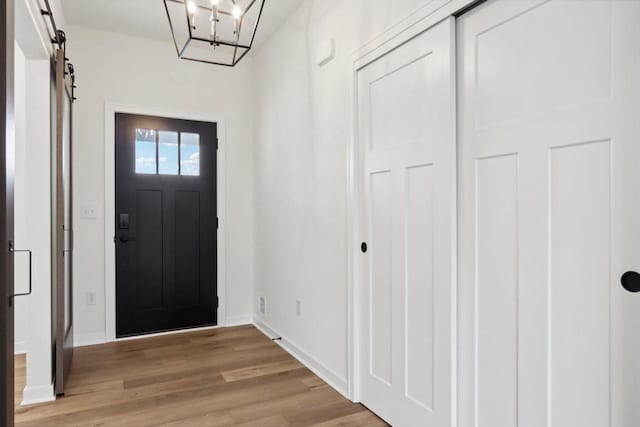 entrance foyer with a barn door, light wood-type flooring, and an inviting chandelier